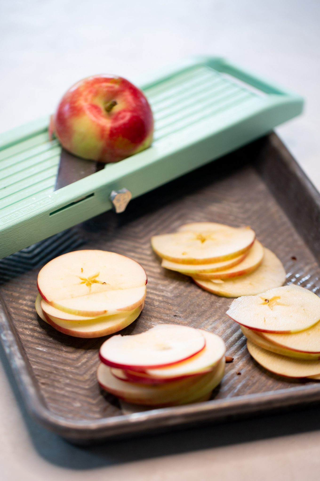 Making apple chips by cutting them with a mandoline