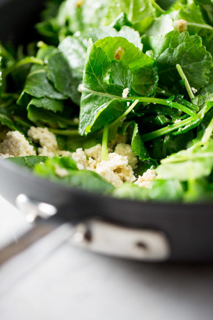 Spinach and kale mix with tofu in a skillet