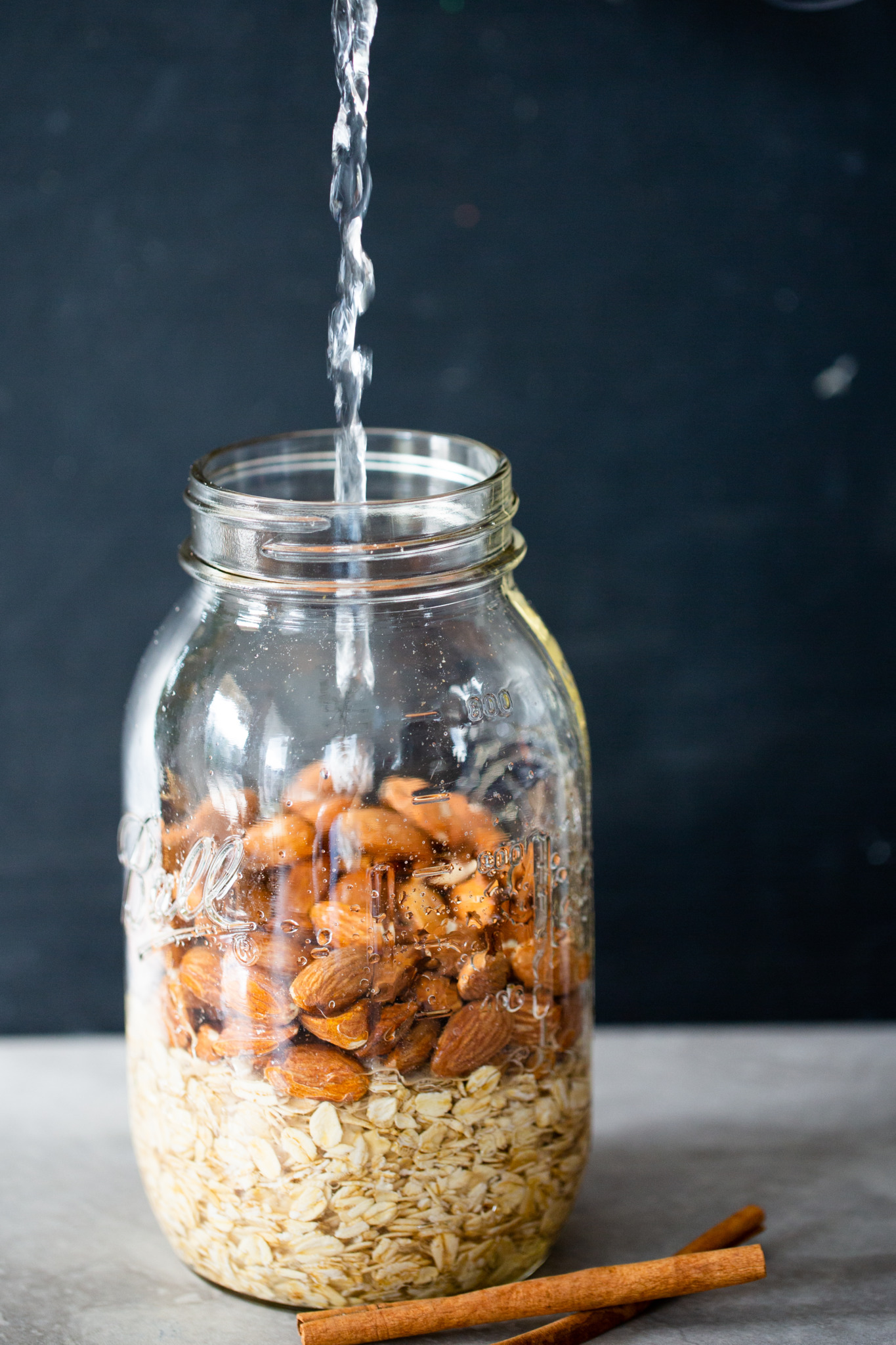 serving water into a jar of oats and almonds