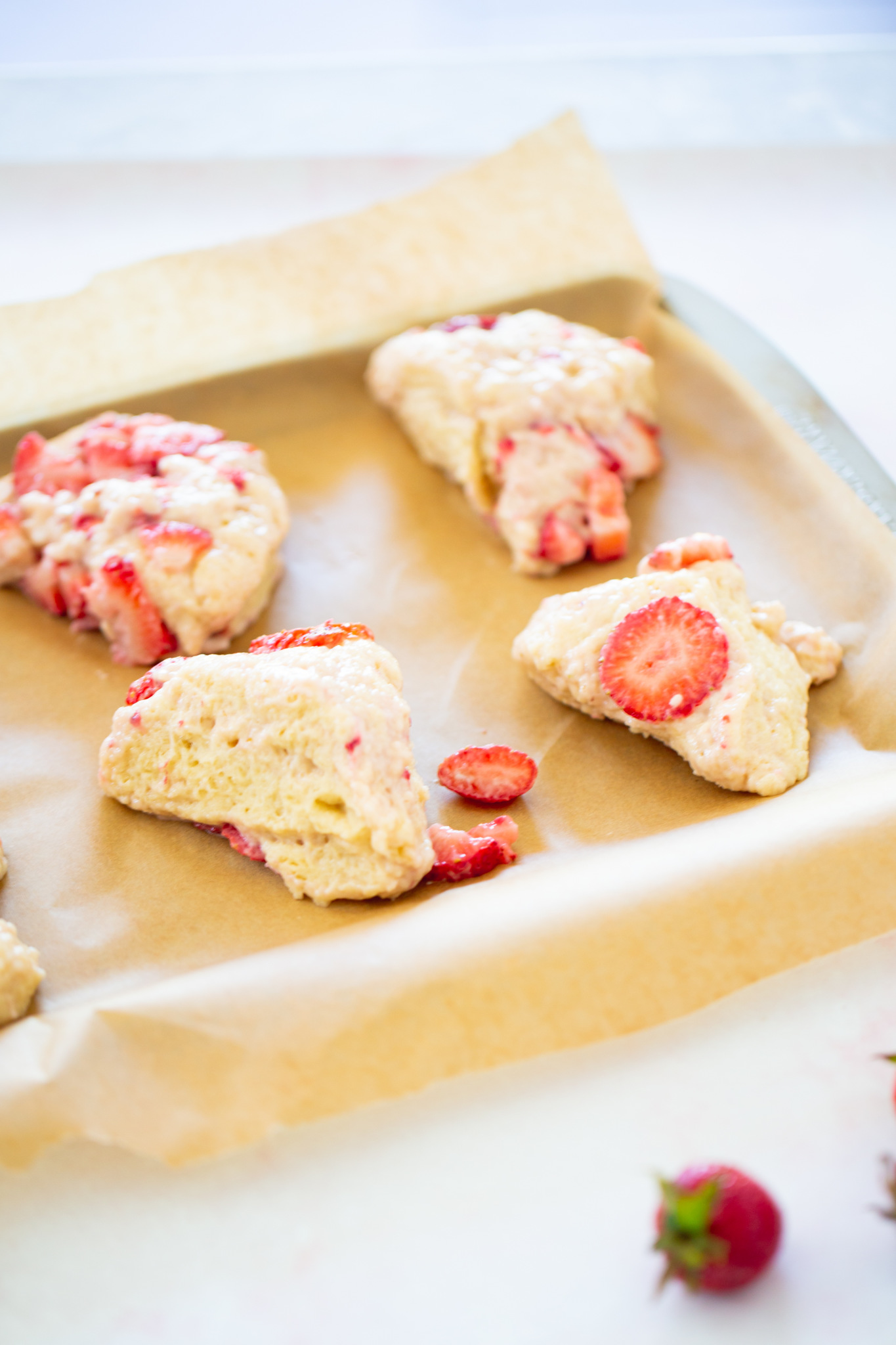 Strawberry scones cut into pieces over a baking sheet with parchment paper
