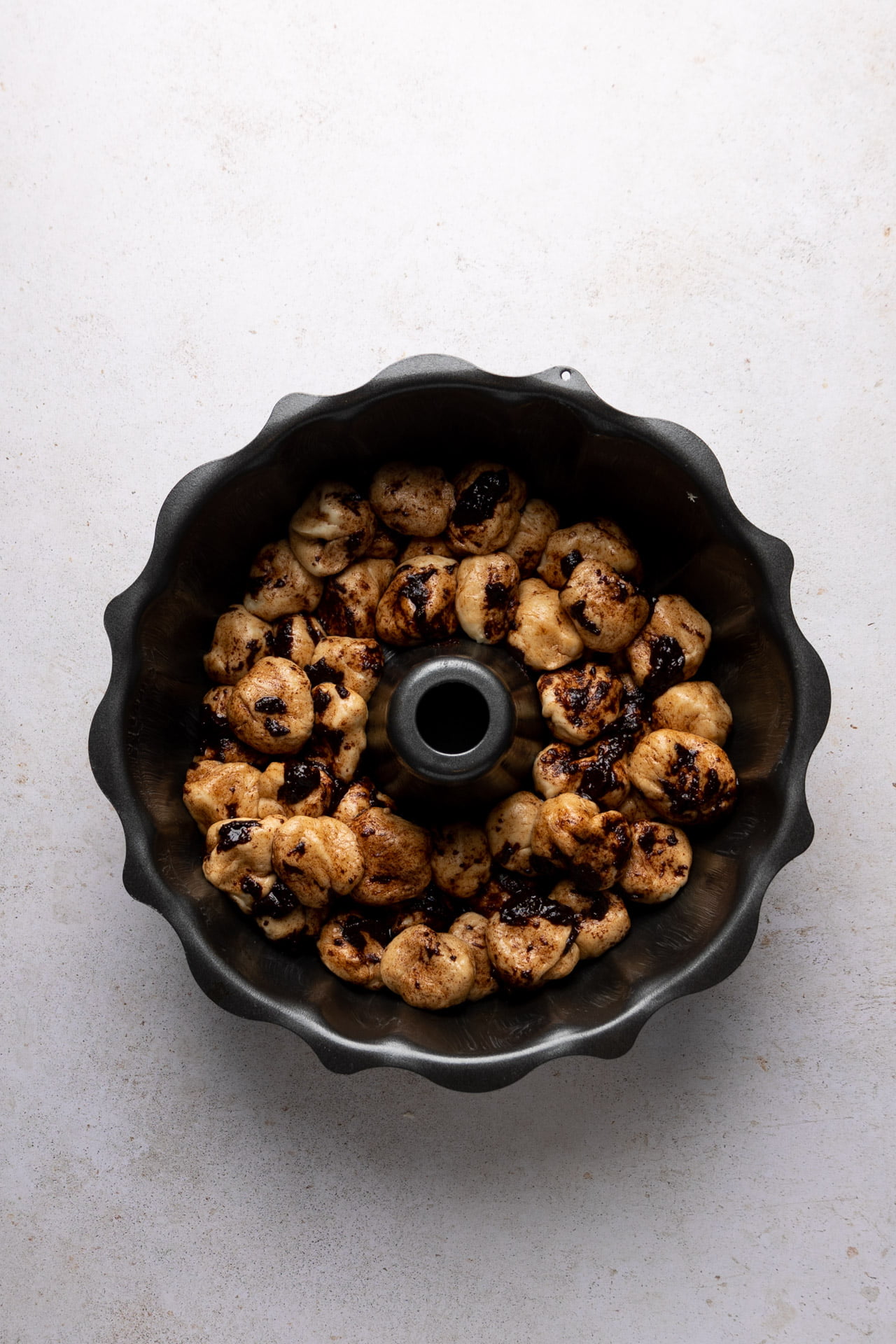 A vegan monkey bread, baked in a cake pan with nuts on a white surface.