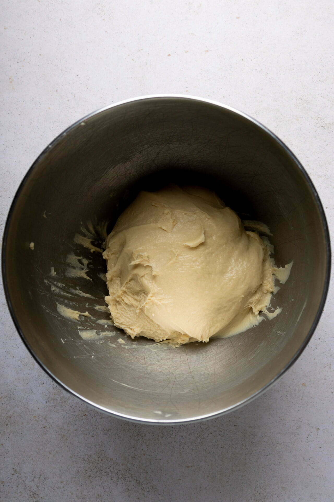 A vegan bowl full of dough on a white surface, ready for vegan baking.