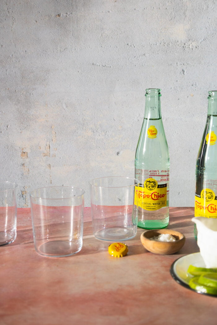 3 empty glasses with topochico bottels and a small dish with salt