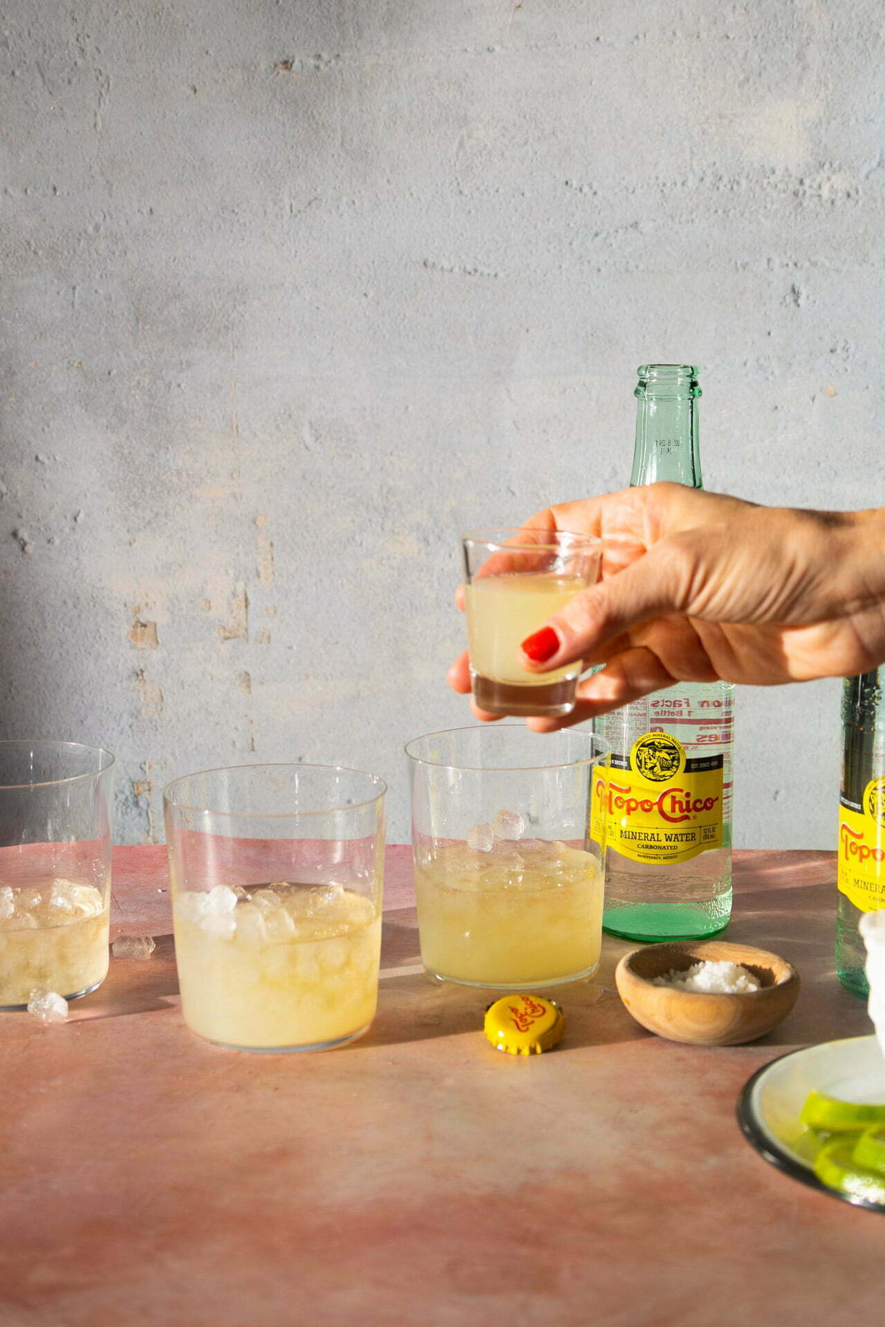 adding lemon juice to a glass with ice and tequila