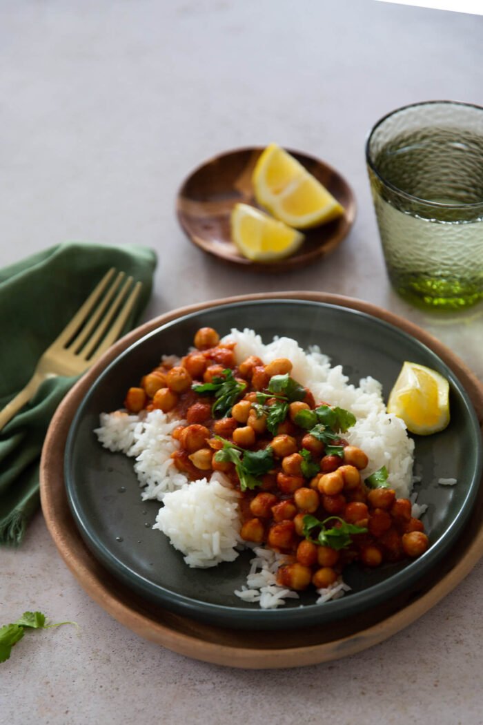 Chana masala on a dark green dish with white rice and topped with cilantro.