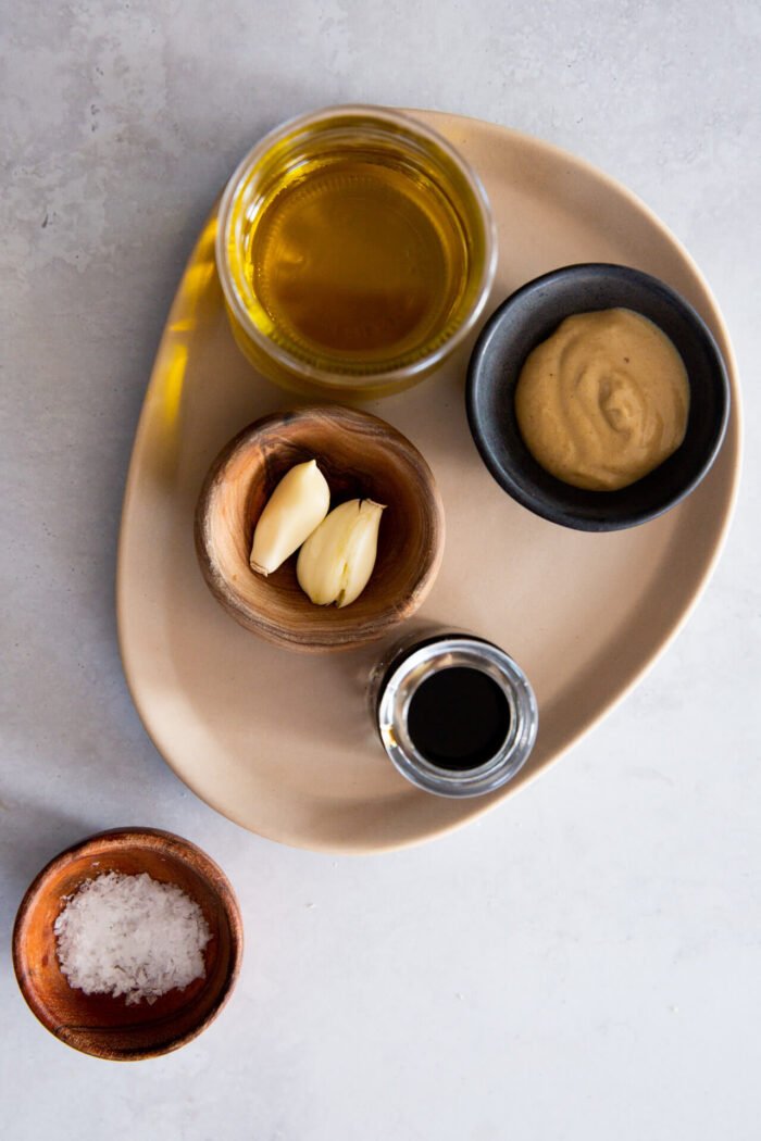 mostaza de dijon, ajo, aceite de oliva y vinagre balsámico medidos para hacer la vinagreta balsámica