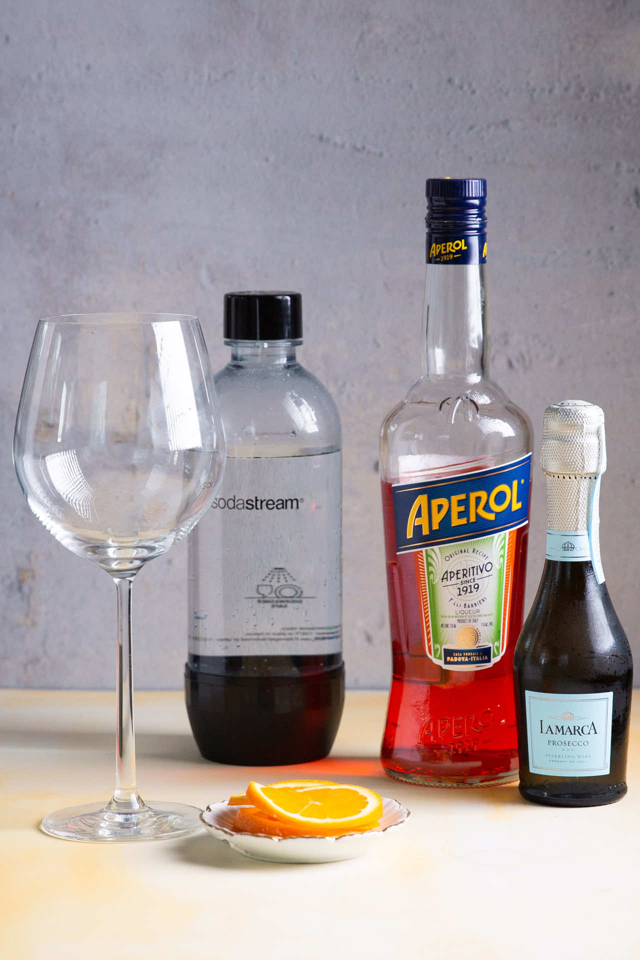 empty wine glass, soda bottle, aperol bottles and proseco bottle
