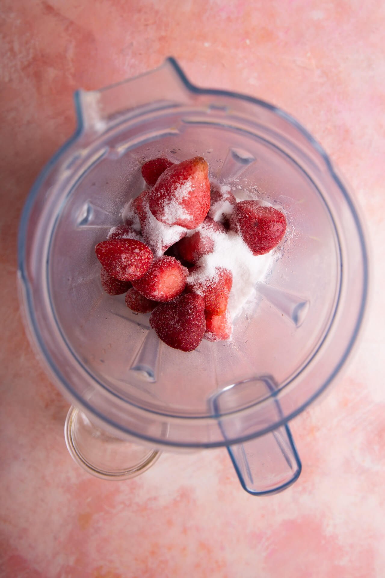 frozen strawberries and sguar in blender container