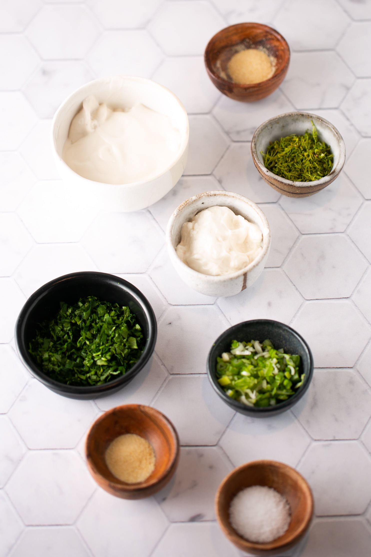 fresh herbs in small bowls, mayo and yogurt in bowls to make homemade ranch dressing