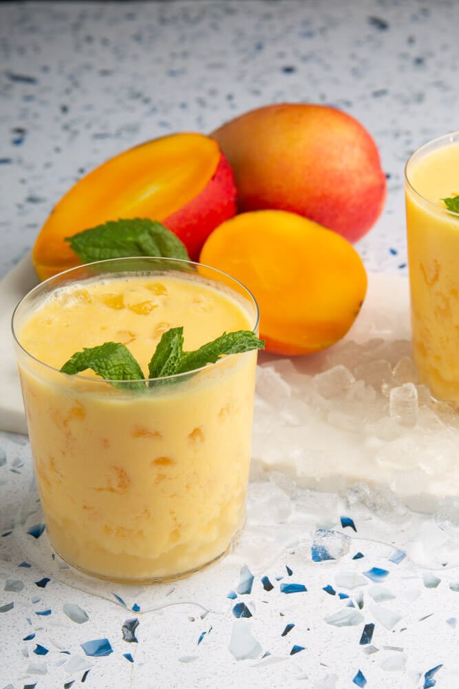 glass with ice and mango lassi decorated with fresh mint leaves