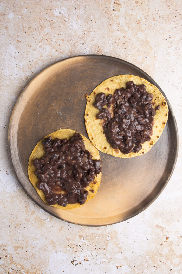 Two corn tortillas with refried beans