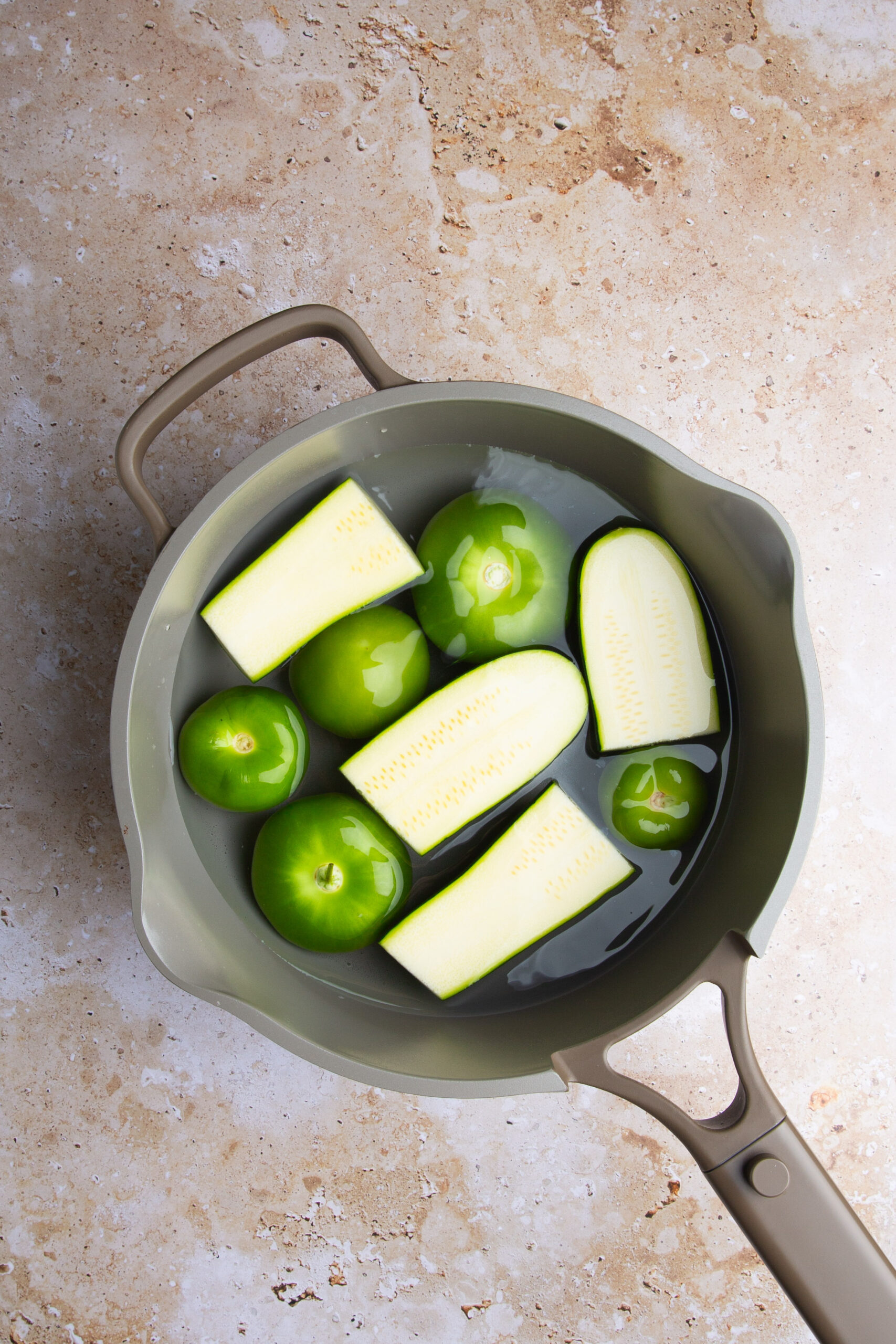 tomatillos and zucchini in a pot with water