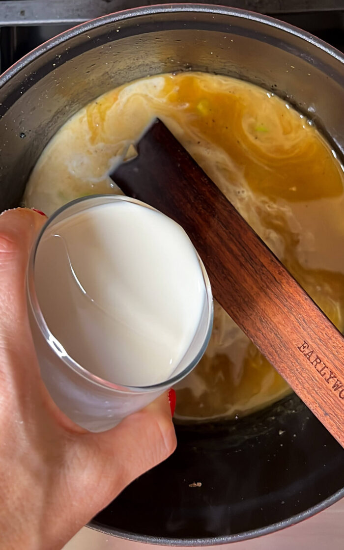 A person pouring deliciously creamy milk into a pot.