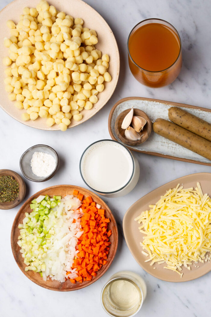 The ingredients for a deliciously creamy vegan sausage pasta dish are laid out on a table.