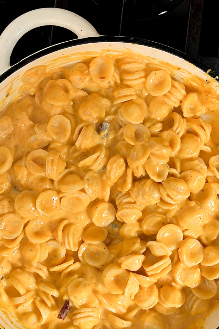 A creamy pot of vegan macaroni and cheese simmering on a stove.