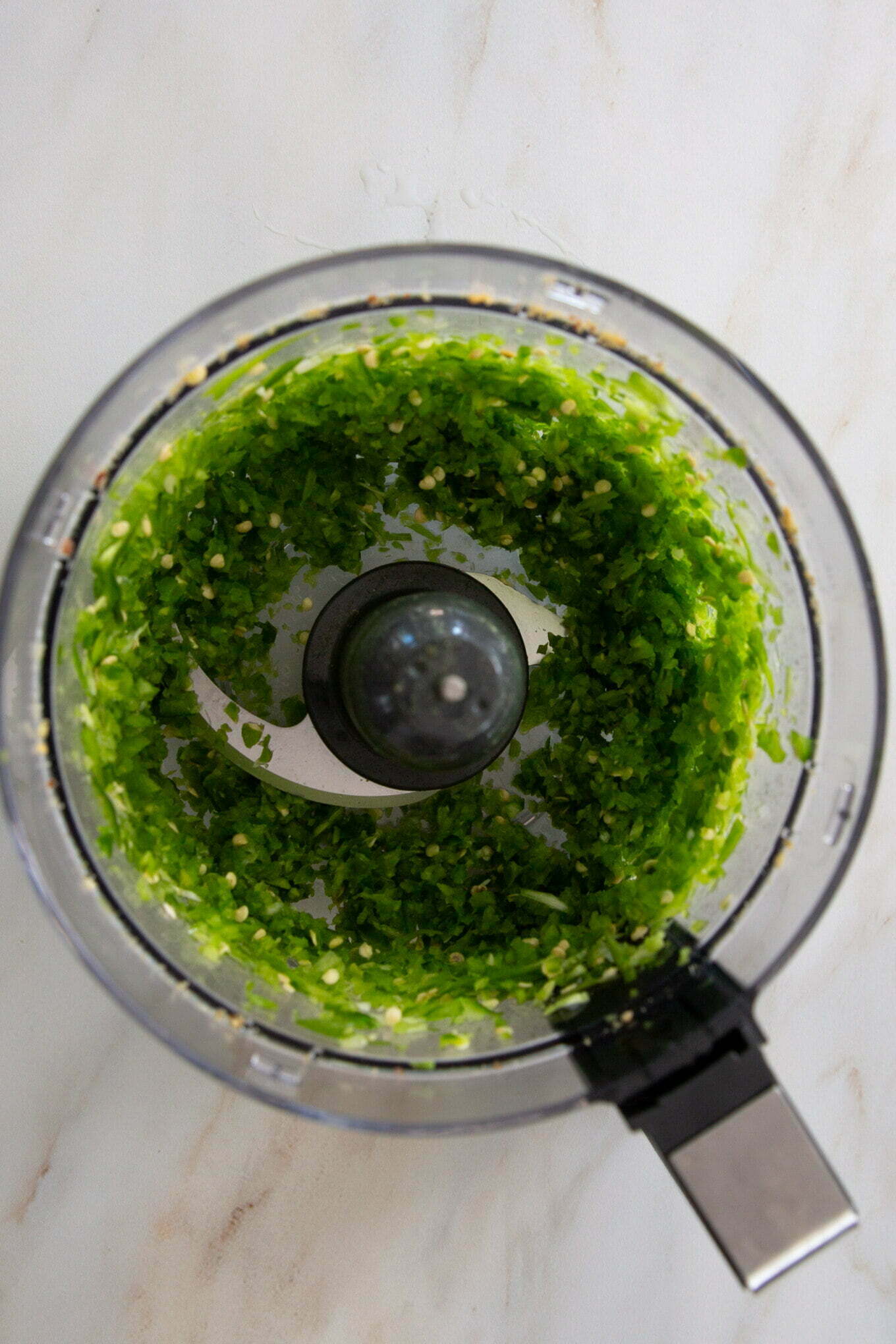 A food processor filled with greens.