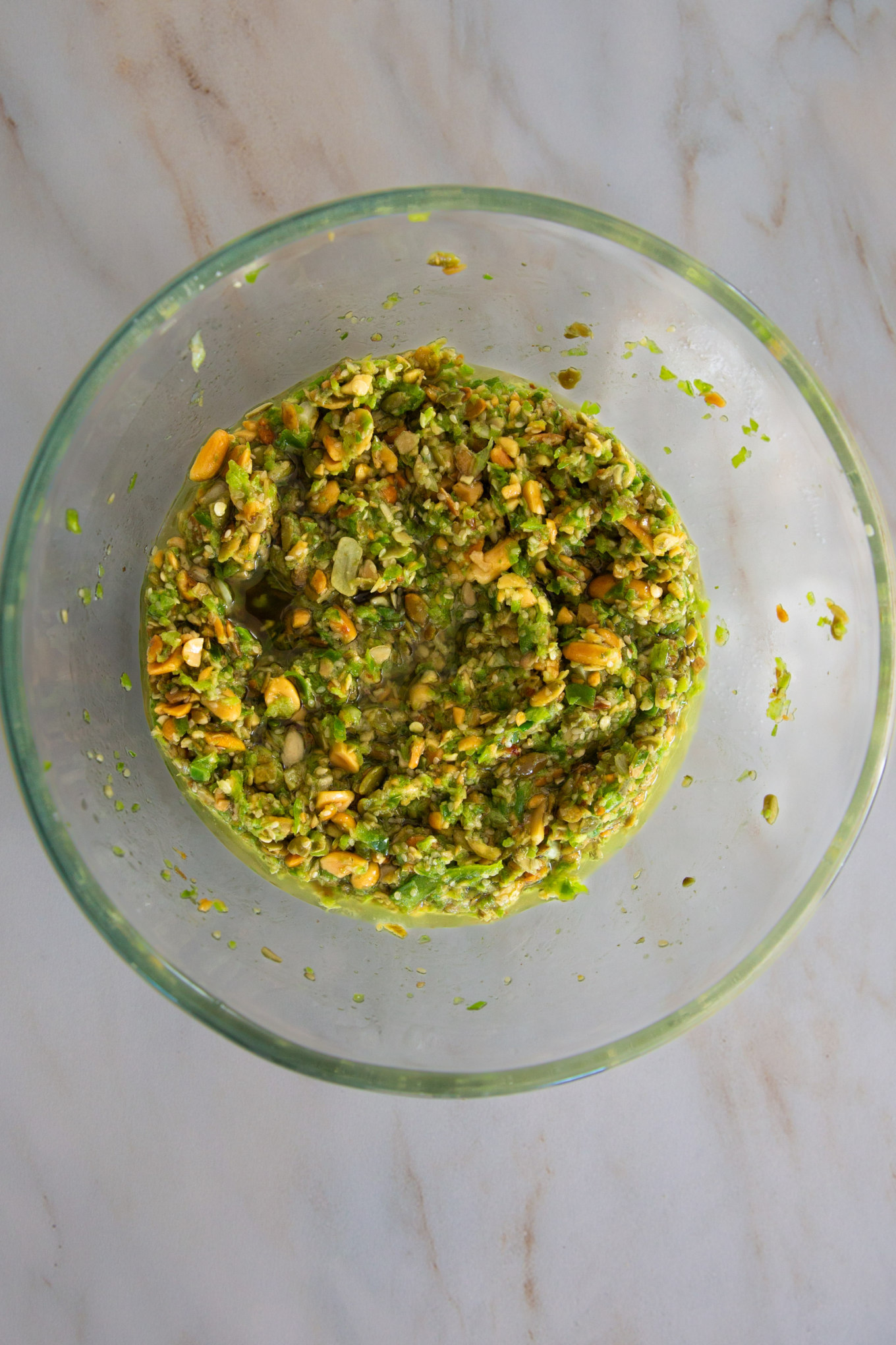 A bowl of freshly made chunky Salsa Macha Verde on a marble surface.