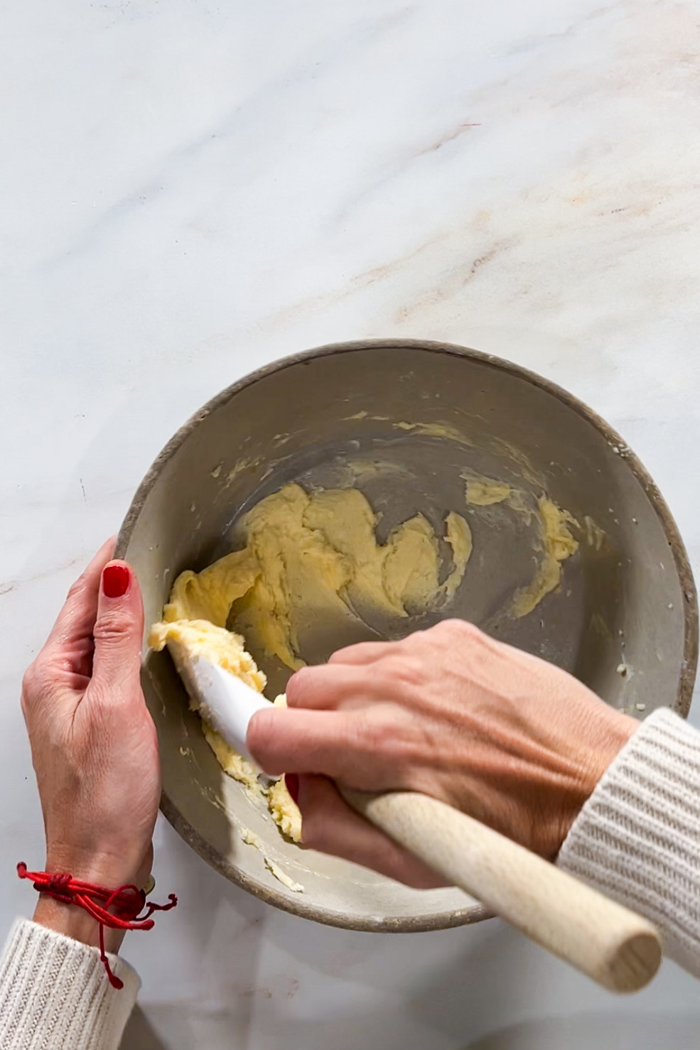 A person kneading butter in a bowl while preparing cookies.