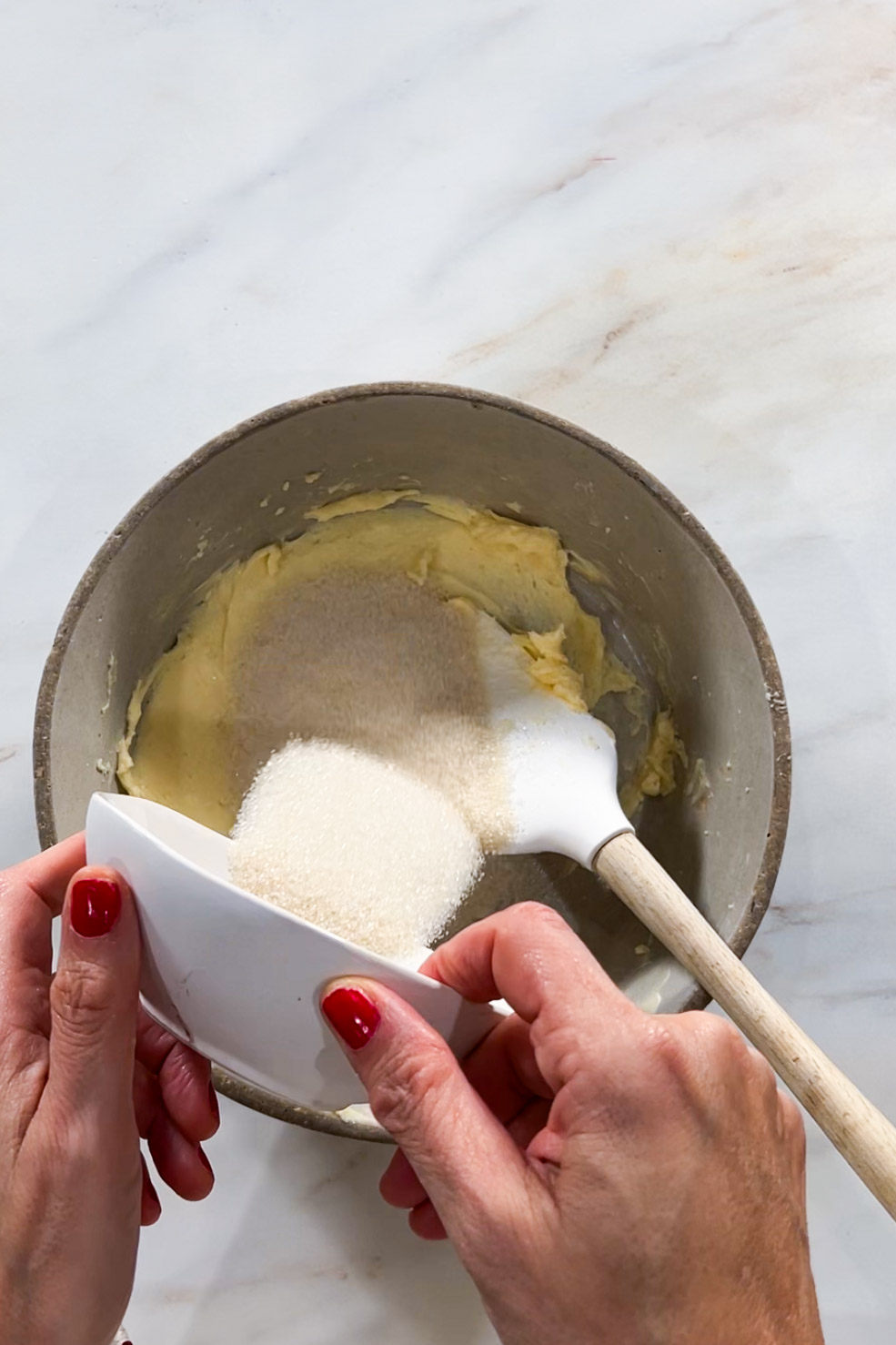 A person mixing sugar and flour in a bowl to make delicious cookies.