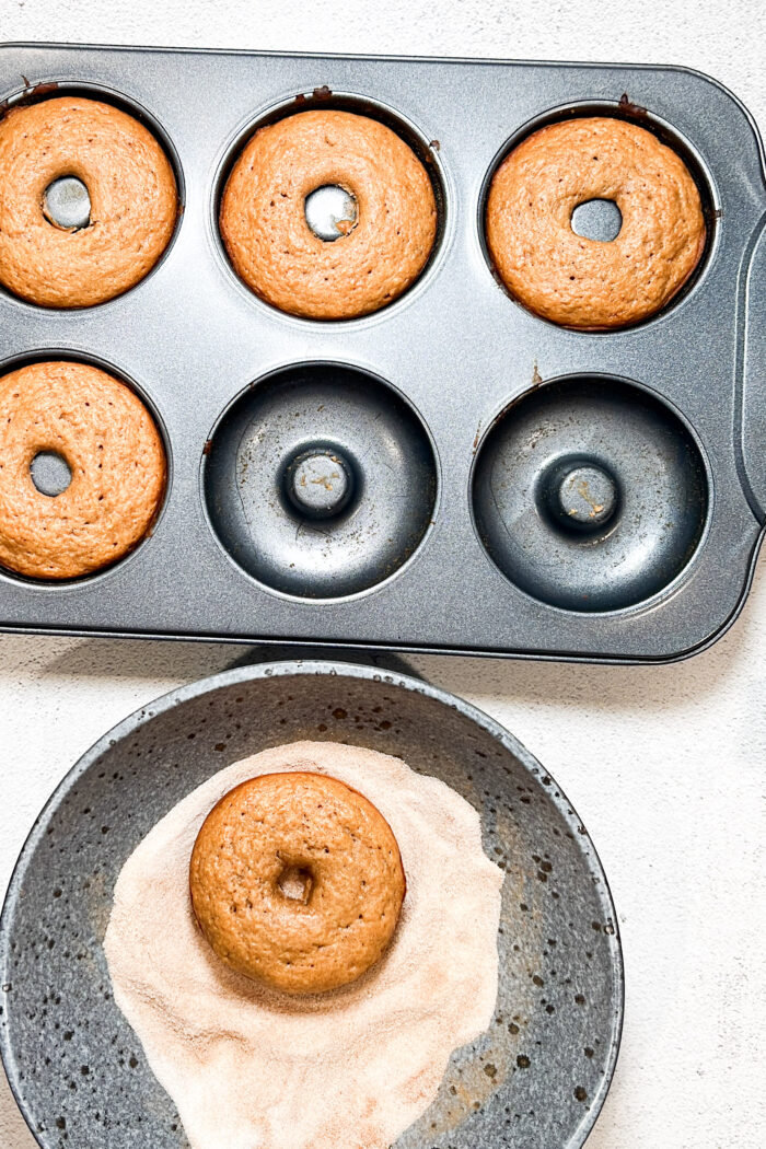 A vegan muffin pan with apple cider donuts in it.