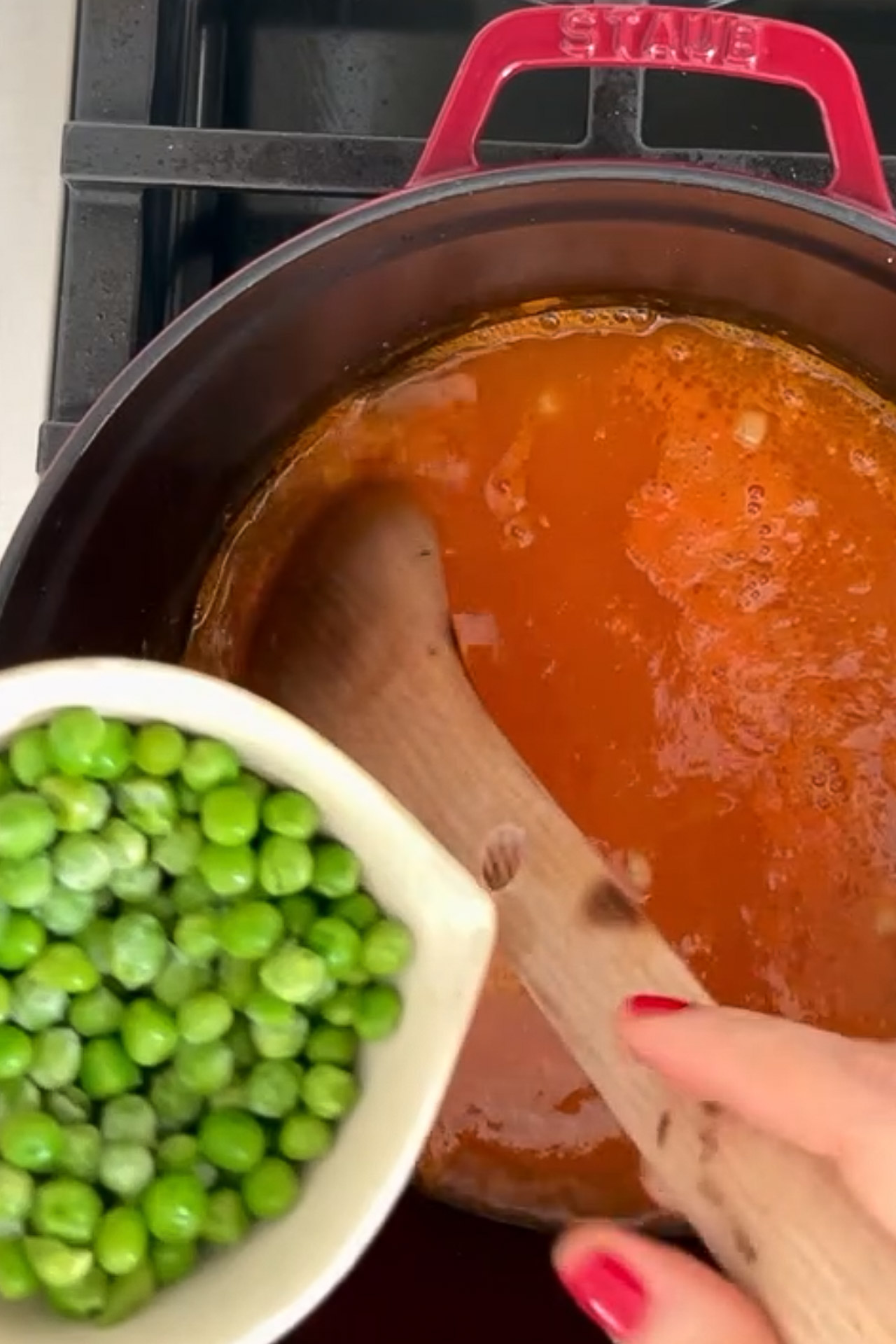 A person easily stirring healthy peas in a pot on the stove to prepare Sopa De Verduras.