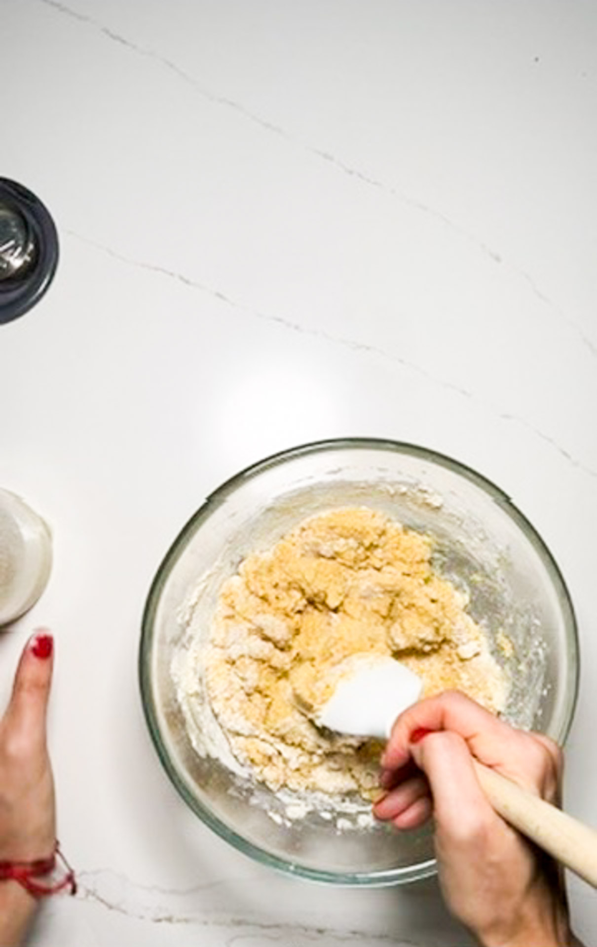 A person mixing ingredients in a glass bowl to create a vegan cornbread recipe.