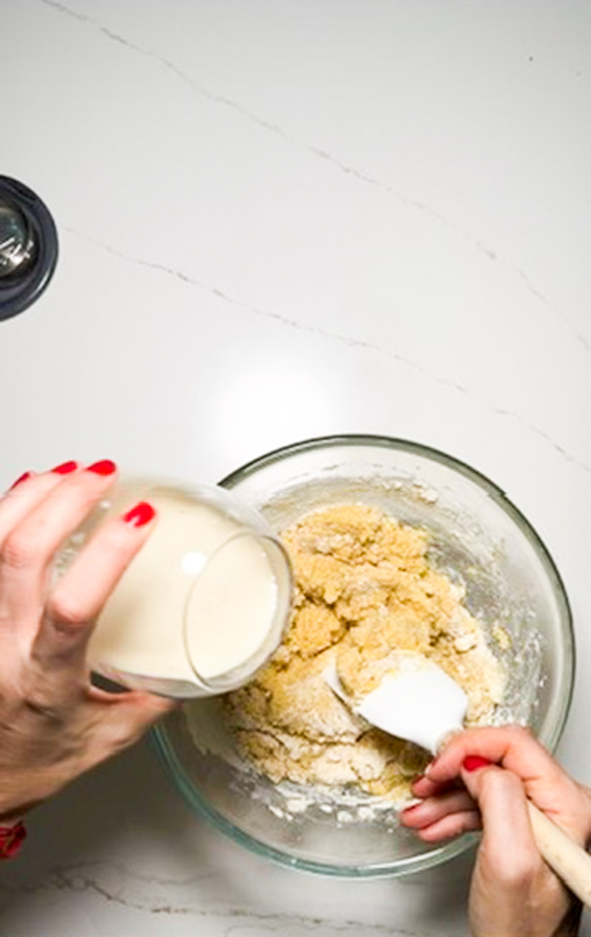 A vegan woman pouring milk into a bowl of dough for a cornbread recipe.