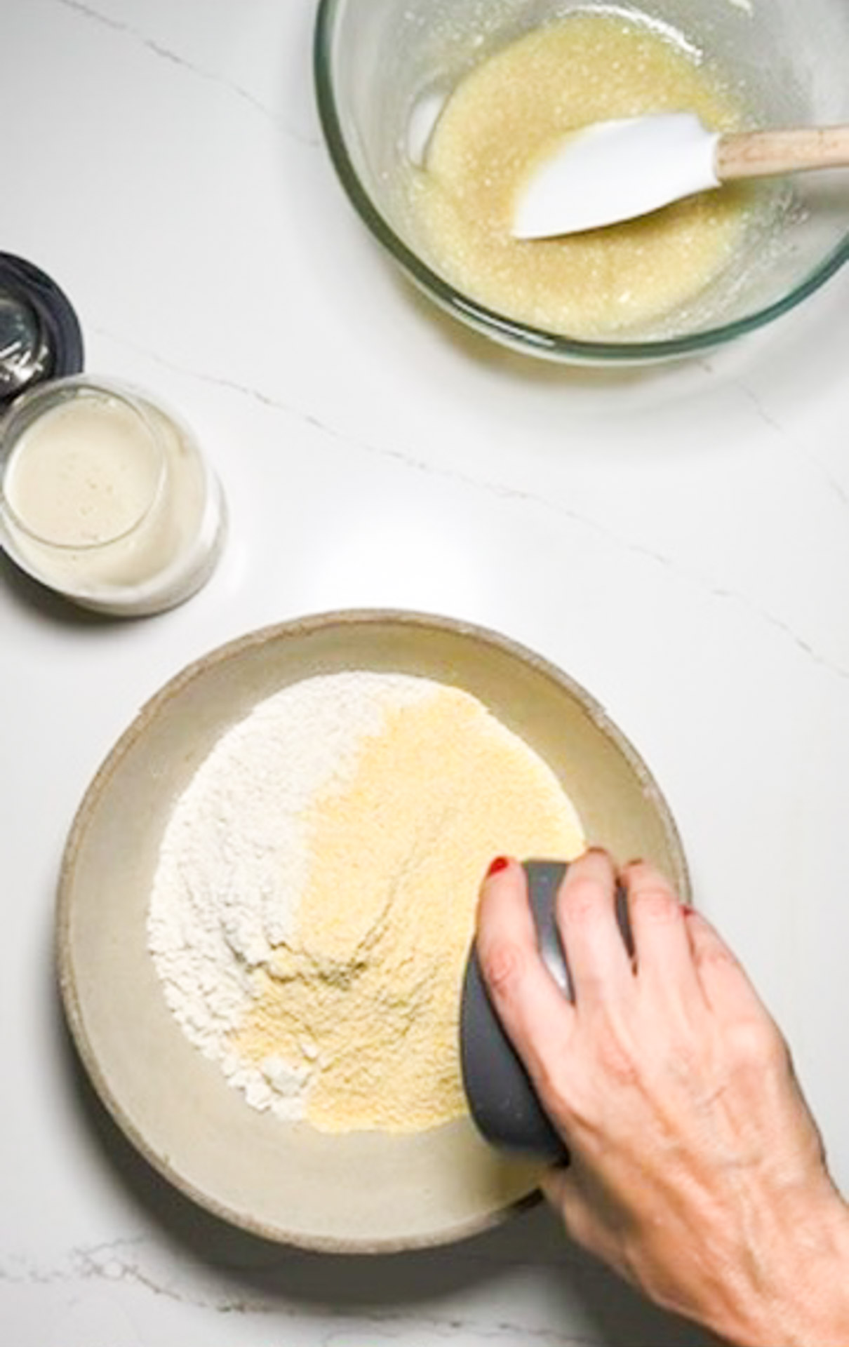 A vegan person mixing ingredients in a bowl to prepare a cornbread recipe.