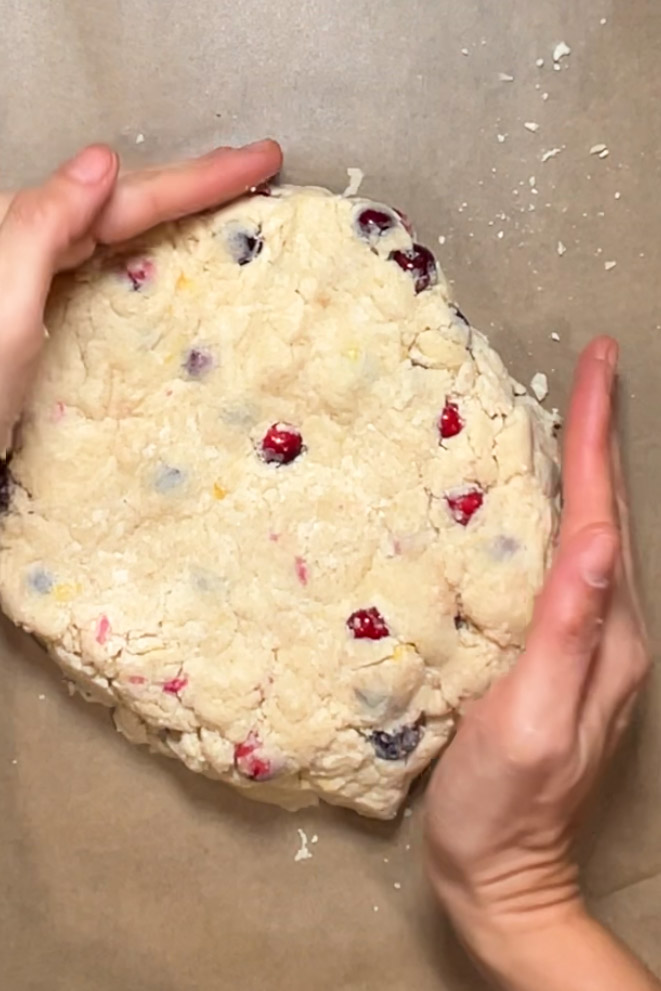 A vegan person adding cranberries to scone dough.