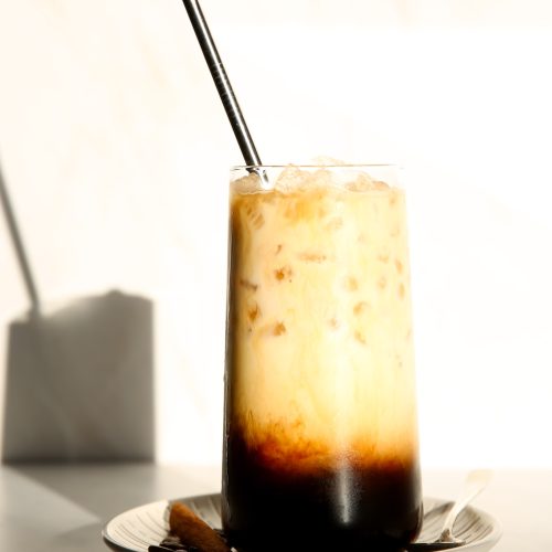 An iced café de olla latte with a straw sitting on a plate.