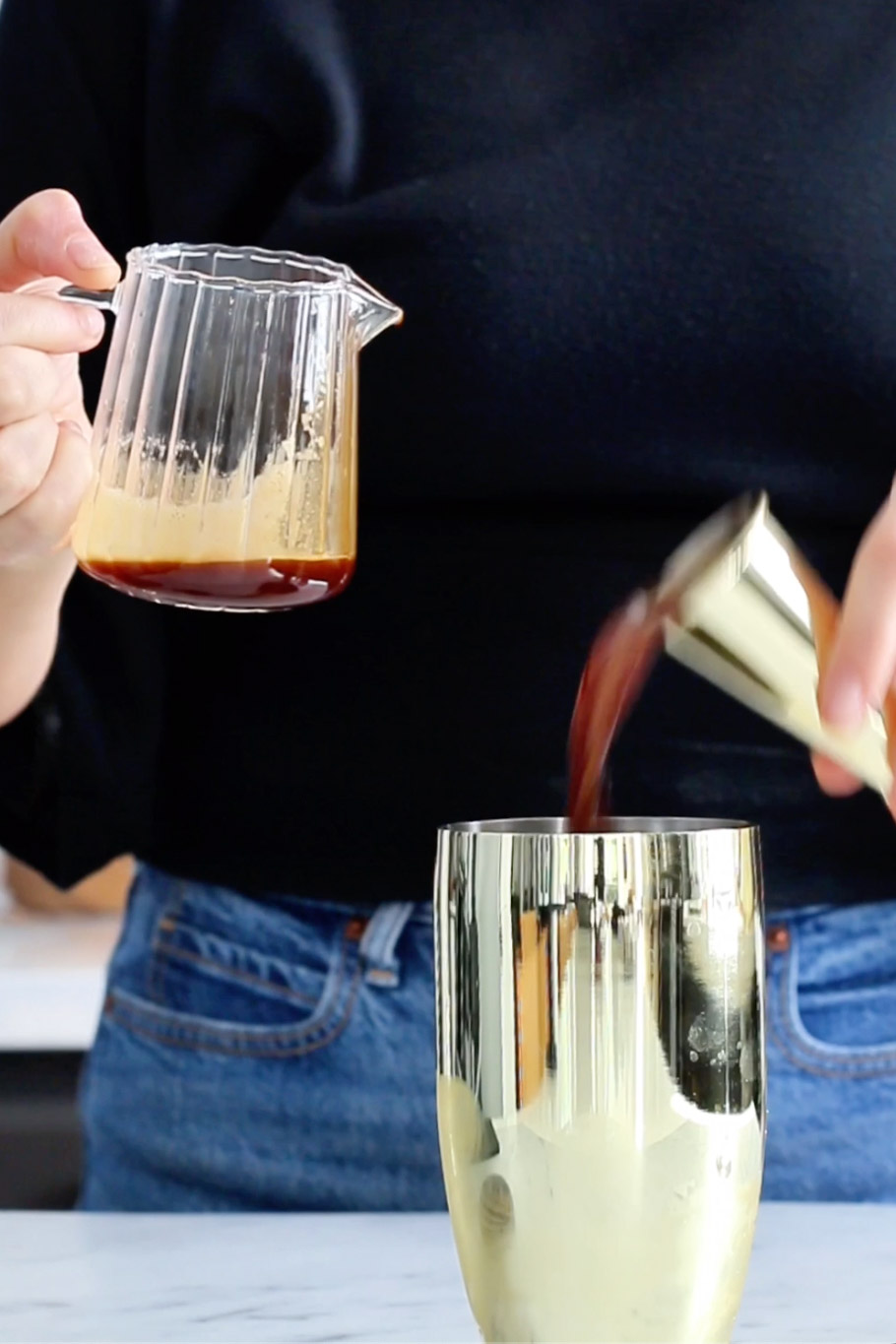 A woman carefully pouring shakeado liquid into a gold cup.