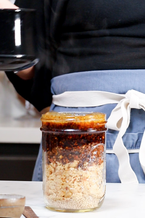 A woman is pouring rice into a jar while following a recipe.