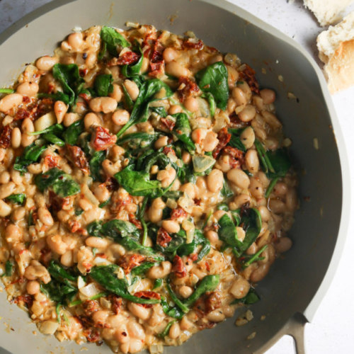White beans and spinach in a skillet.