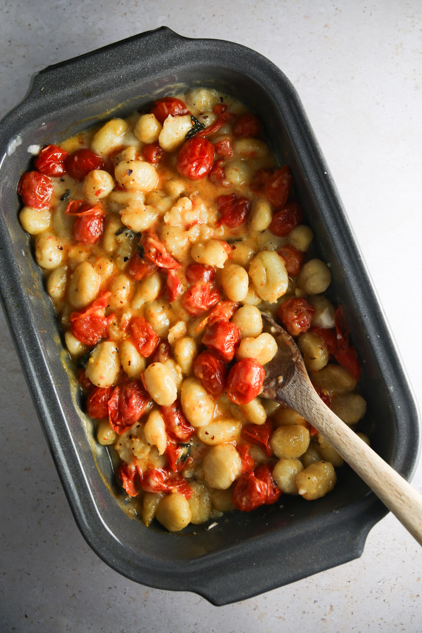 A baking dish filled with roasted cherry tomatoes and beans.