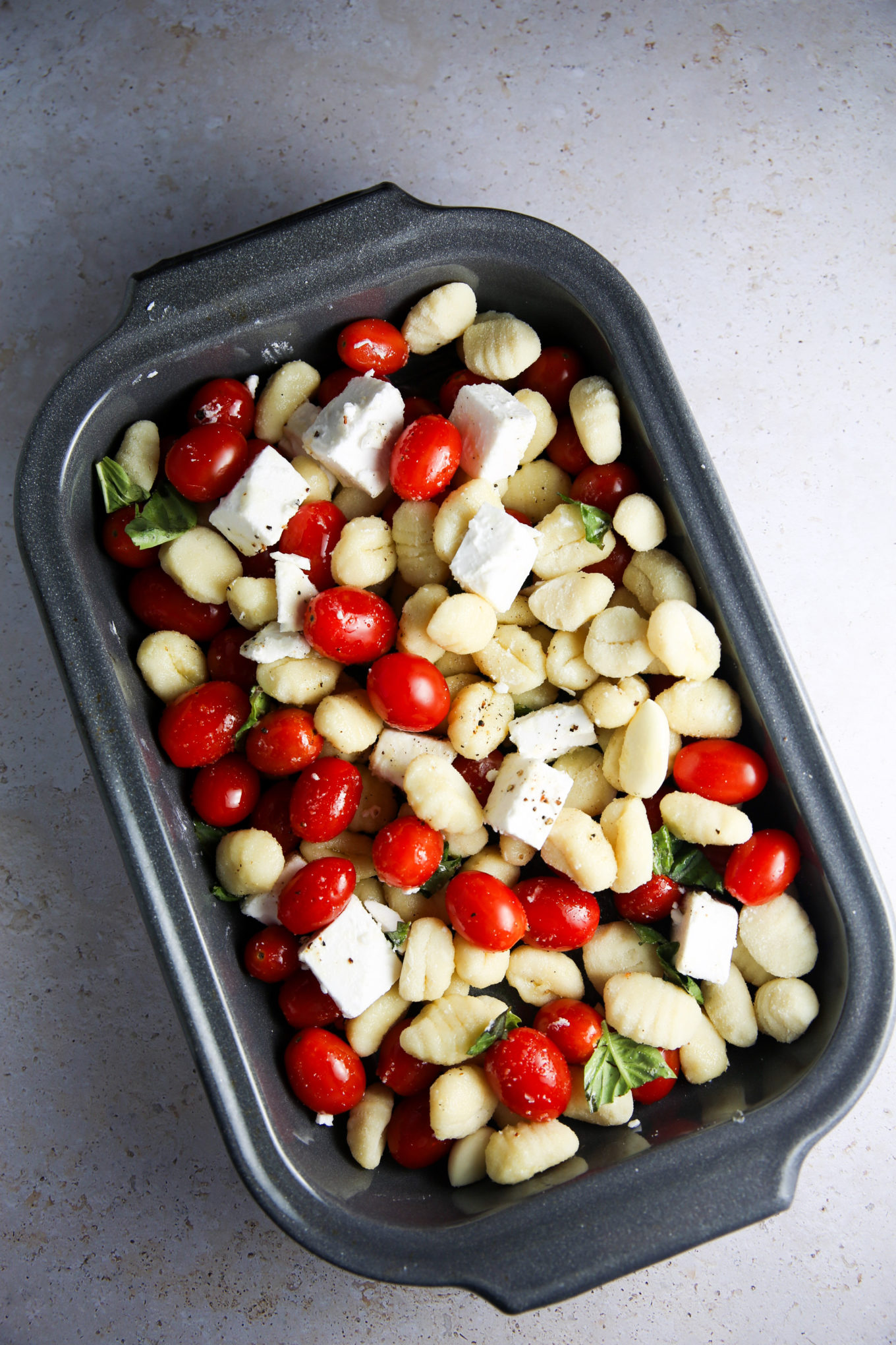 A baked dish filled with cherry tomatoes and feta cheese.