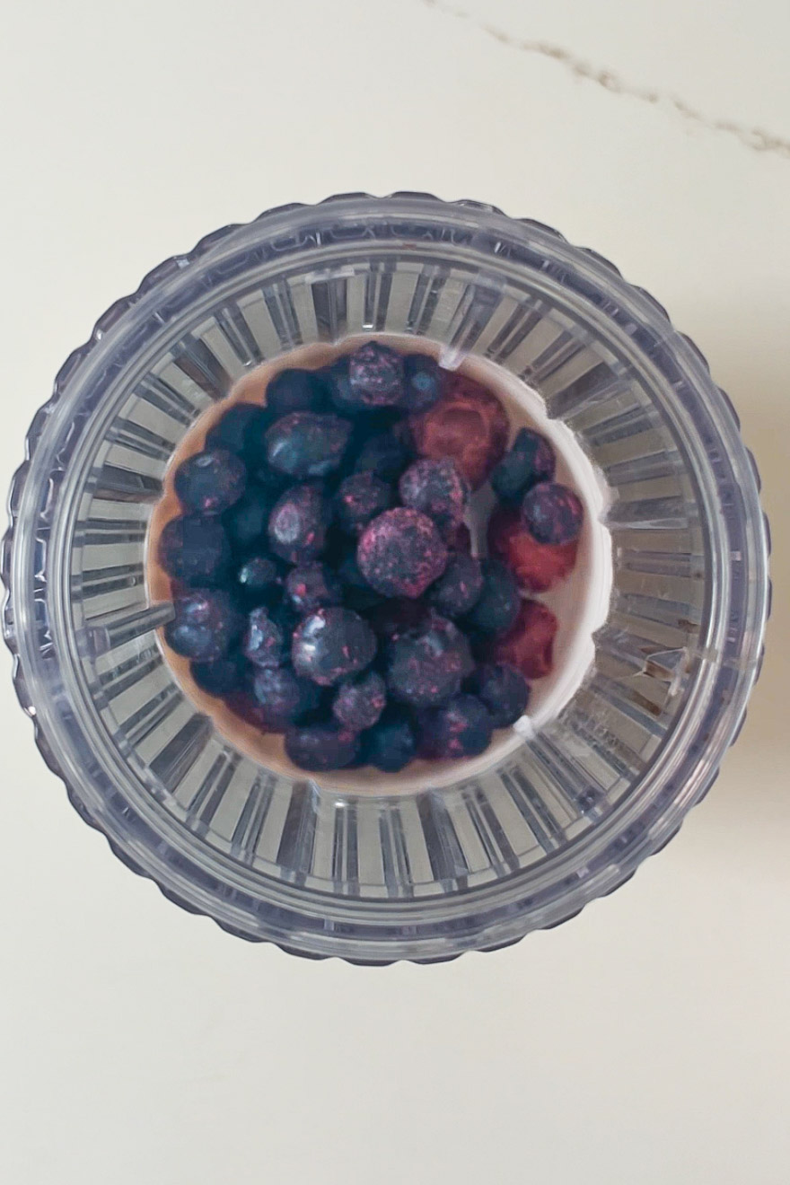 A bowl of yogurt with blueberries and topped with blackberries.