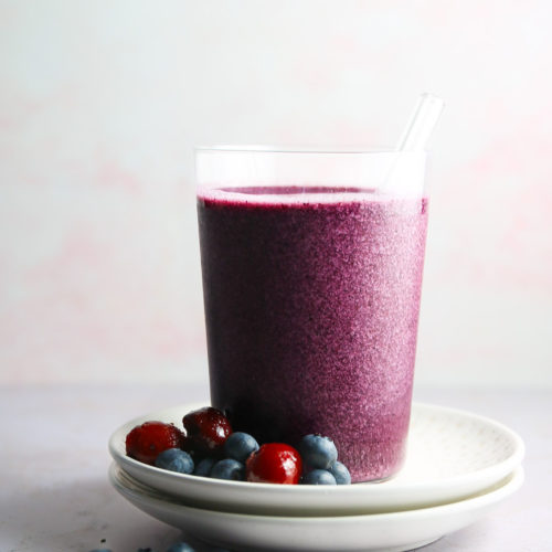A blueberry smoothie with blackberries on a plate.