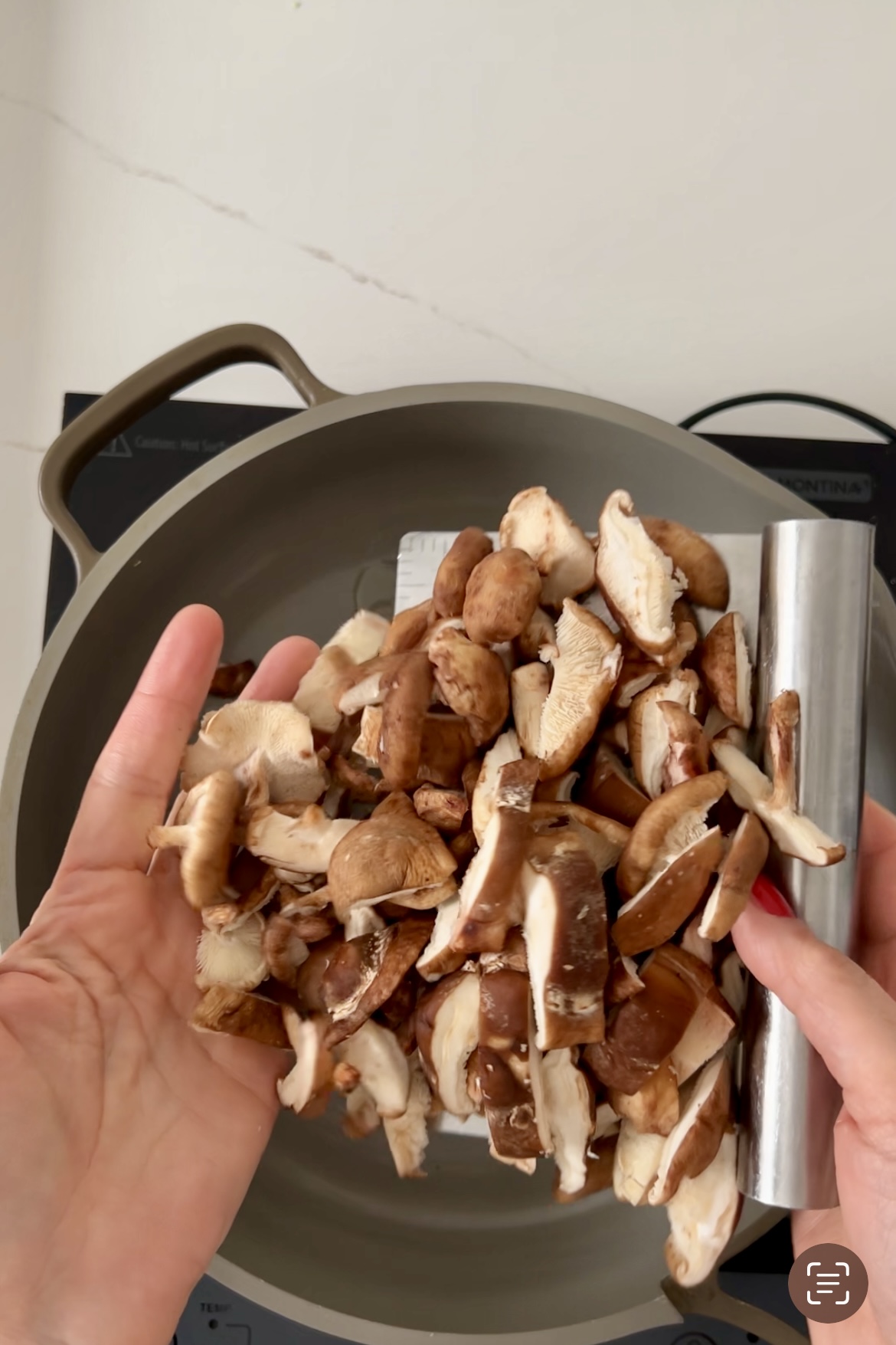 A person is stir-frying mushrooms in a pan.