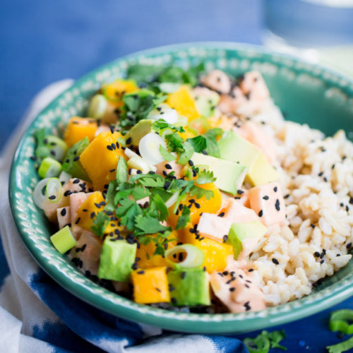A bowl of rice with salmon, mango and avocado.