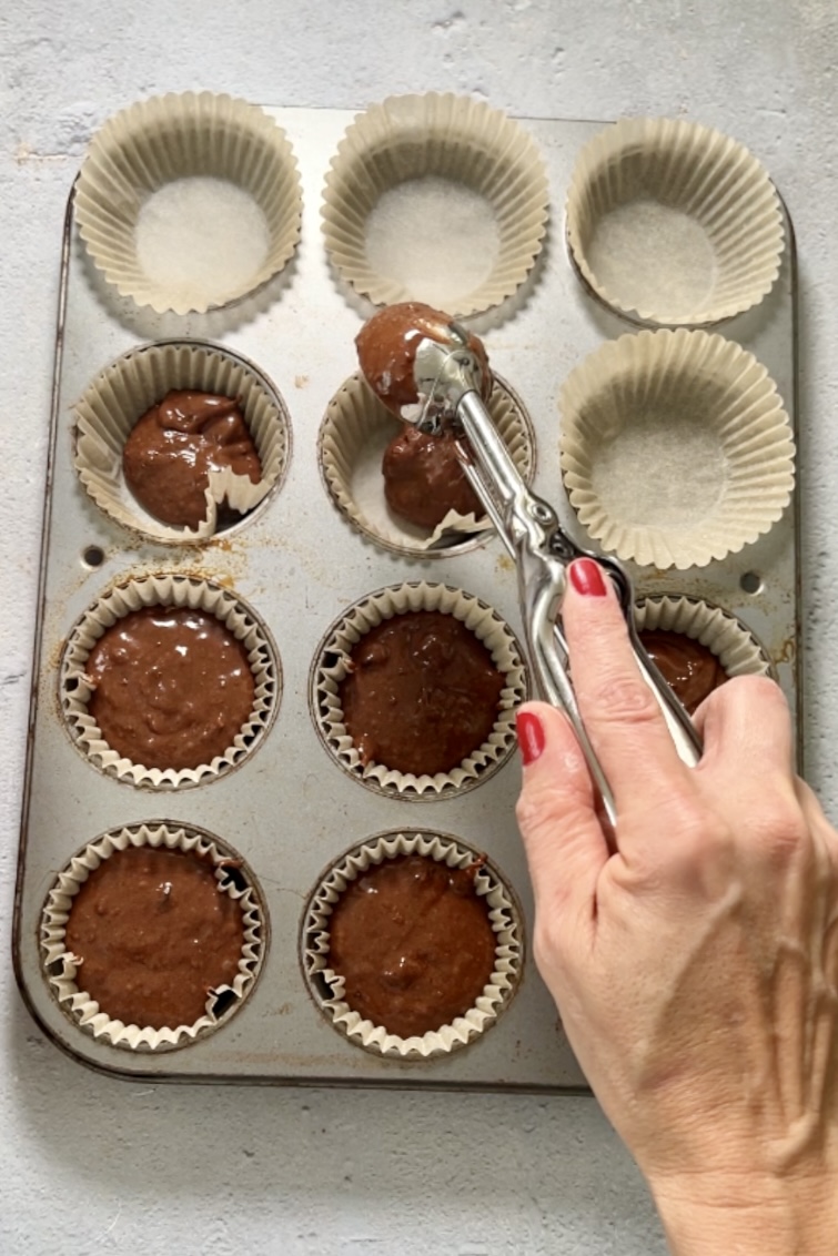 One person pours chocolate into a muffin tin filled with sprinkles.
