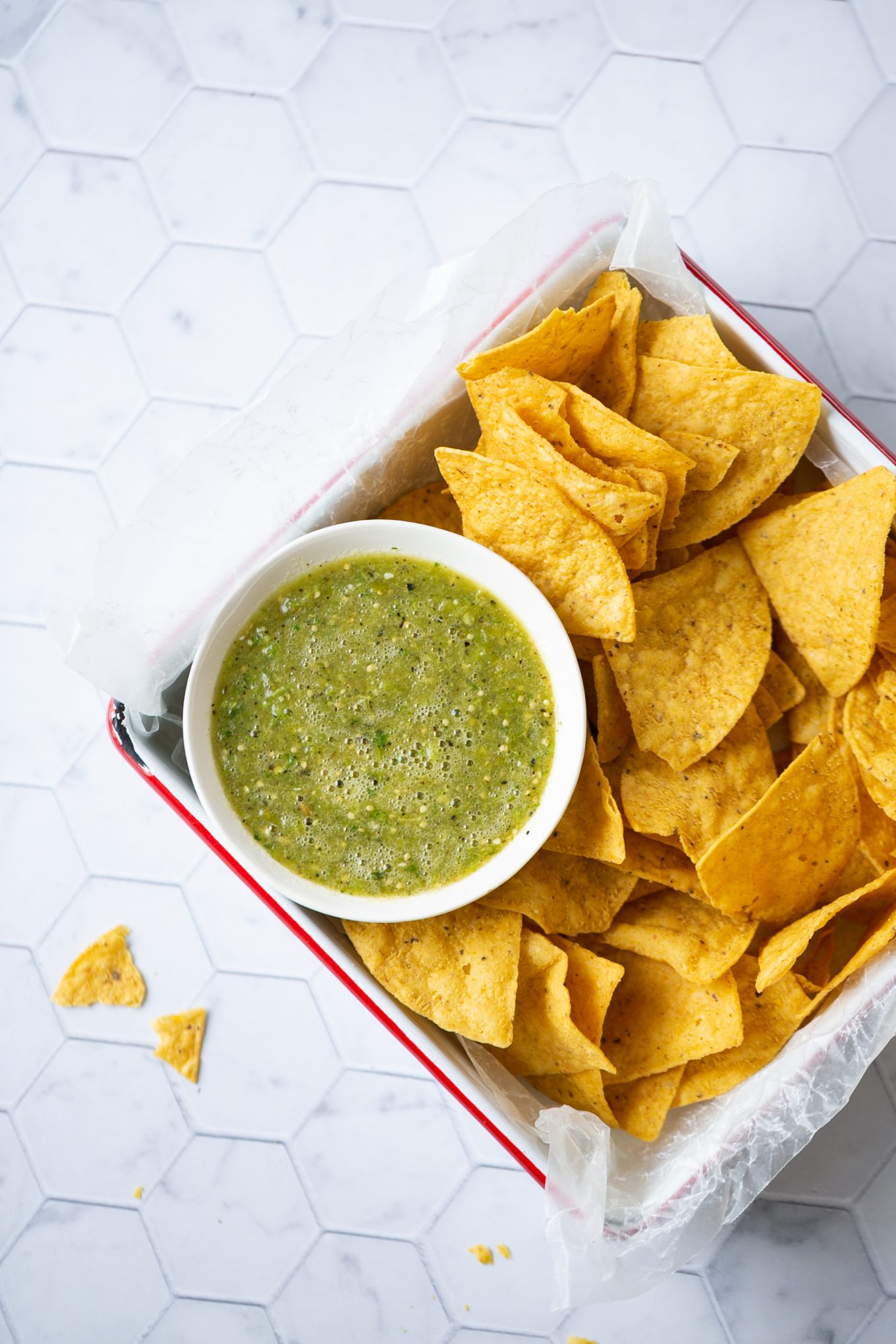 A tray of tortilla chips with authentic Mexican salsa verde and guacamole.