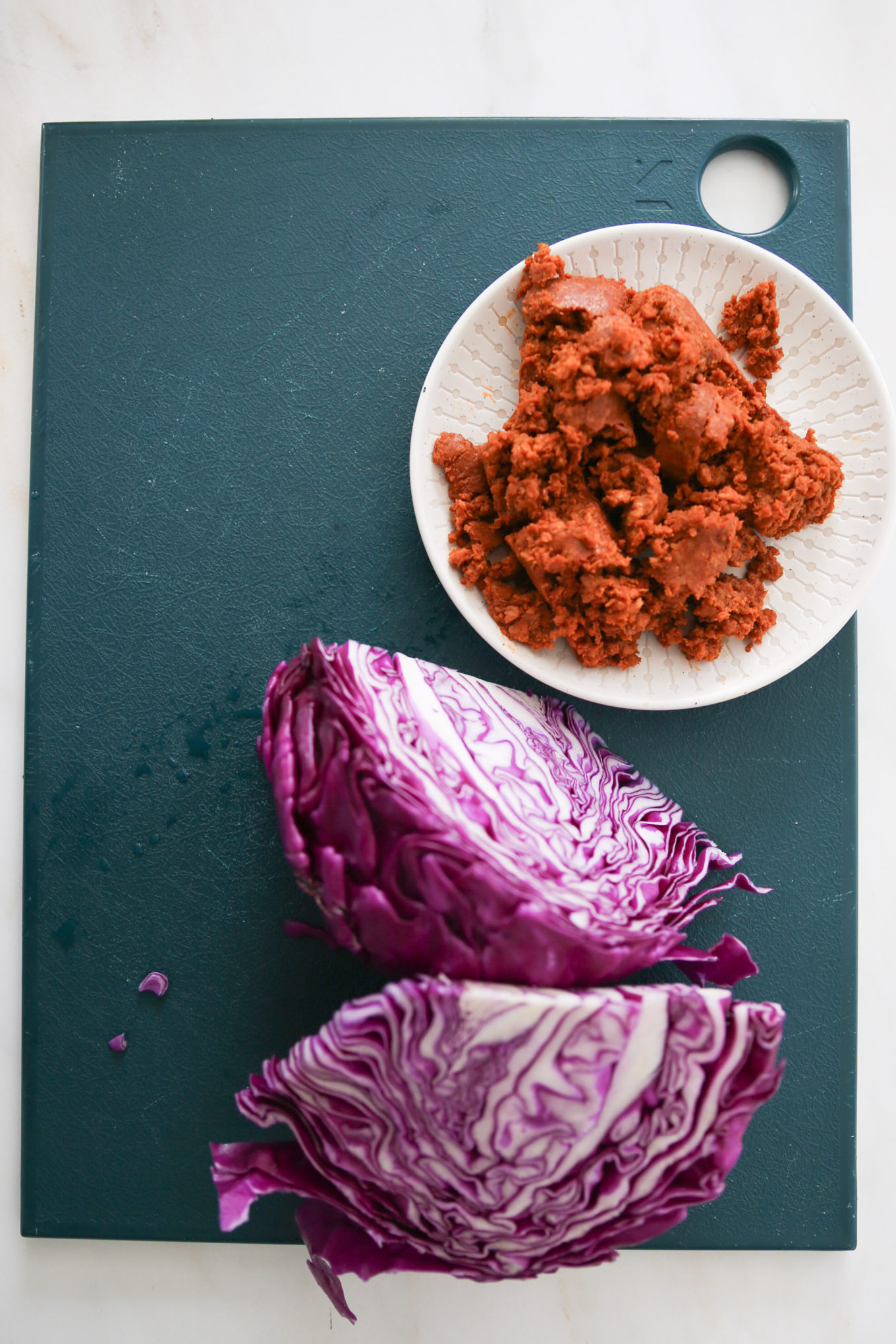 Two quarters of red cabbage and a plate with soy chorizo.
