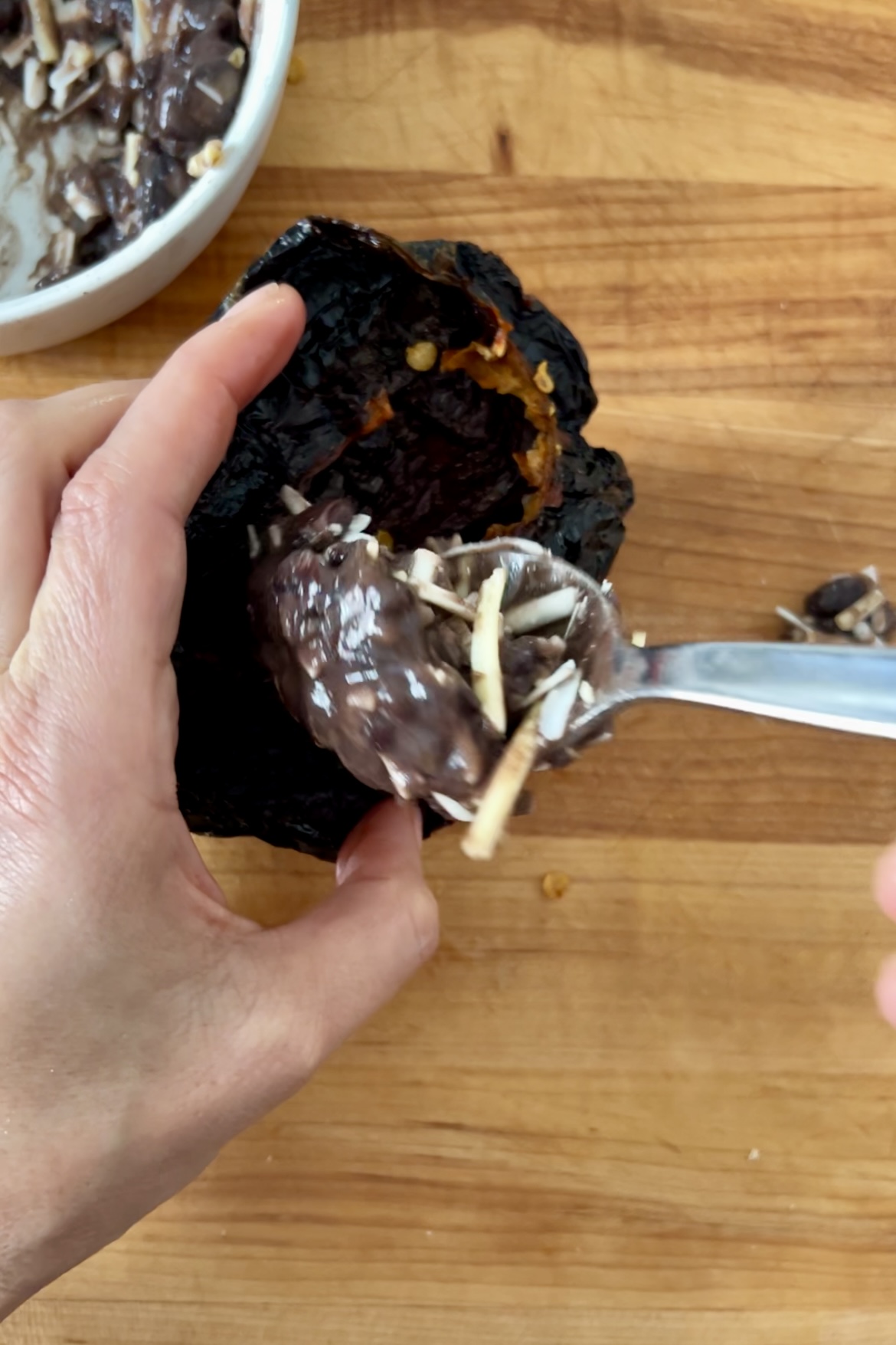 A person using a spoon to eat chocolate-covered ancho chili cakes.