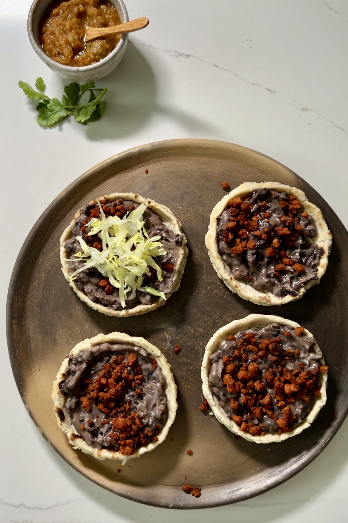 four sopes with refried beans and chorizo and one with shredded lettuce