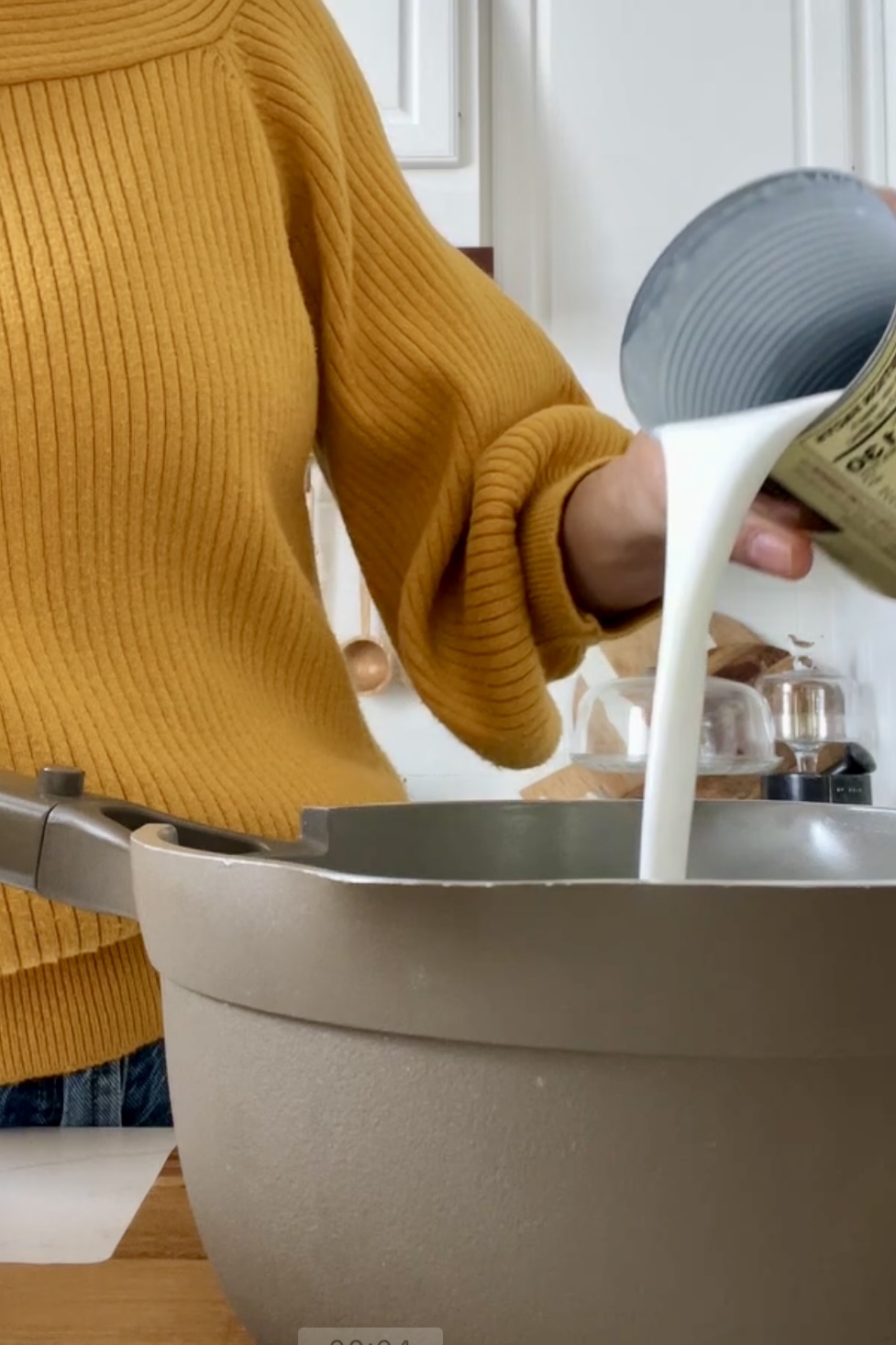 Woman in yellow sweater pouring cocoa milk into a pot