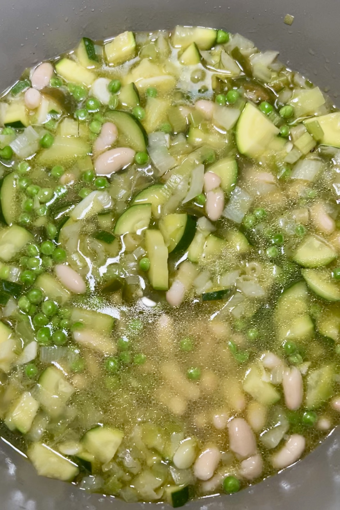 spring minestrone in a pot with cannelini beans, peas and zucchini