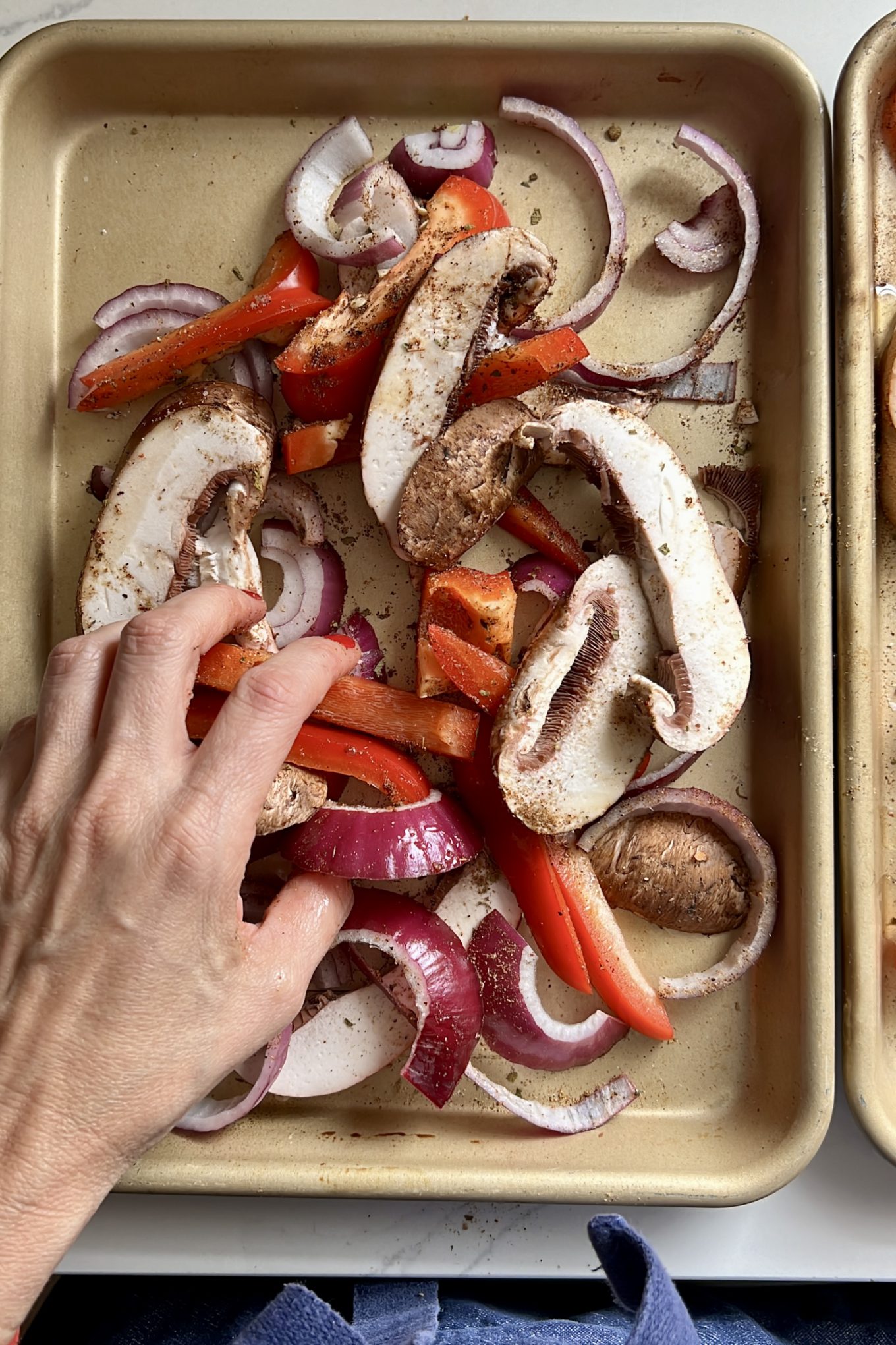 two quarter sheet pans with sliced portobello, red bell pepper and onions and fajita seasonig