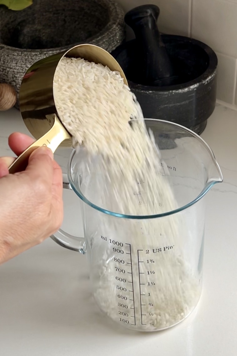 pouring rice into a glass measuring cup